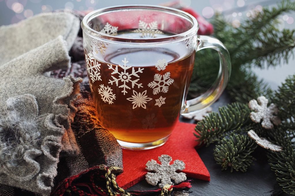 A cup of tea surrounded by pine branches and snowflakes 